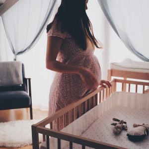 pregnant woman standing over crib