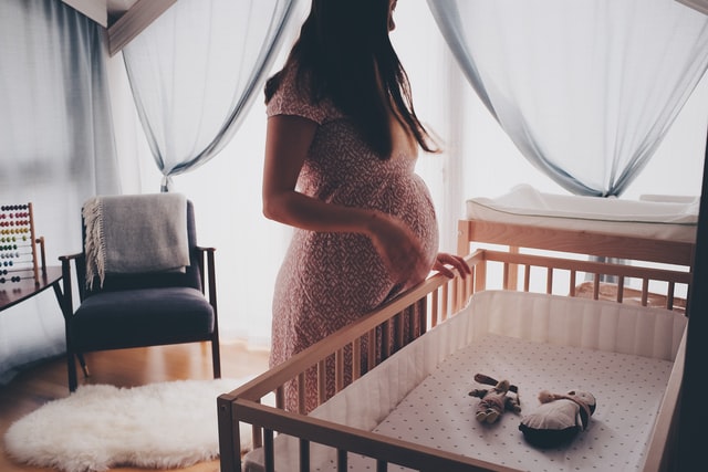 pregnant woman standing over crib
